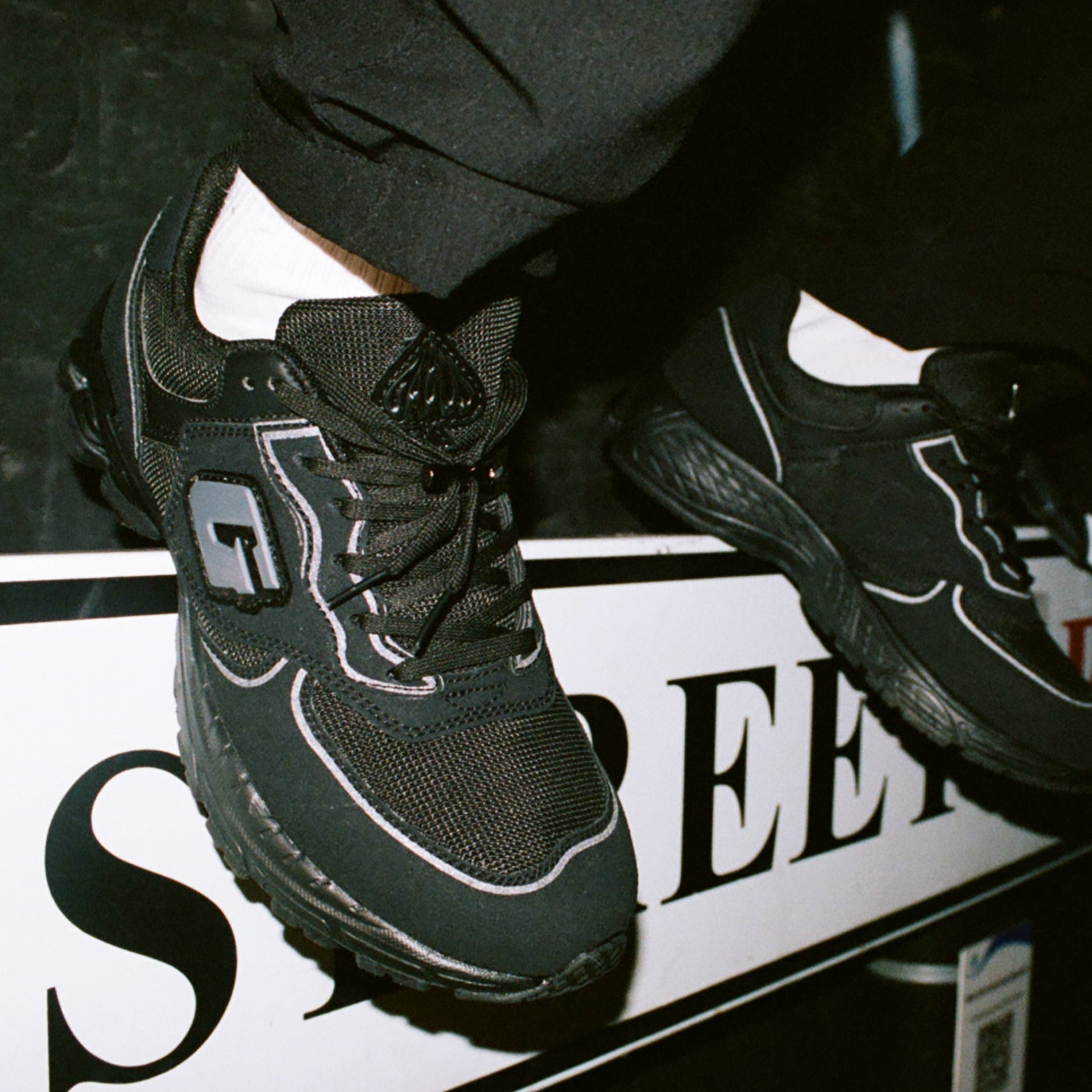 Black sneakers with a brand logo on a dark background