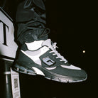 Black and white sneaker with a brand logo on a dark background