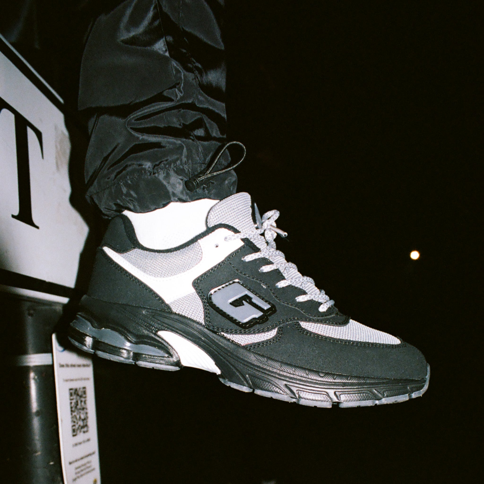 Black and white sneaker with a brand logo on a dark background