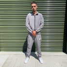 Gabos London grey 3-piece tracksuit set with matching trousers, worn by male model in urban industrial setting – streetwear for SS25