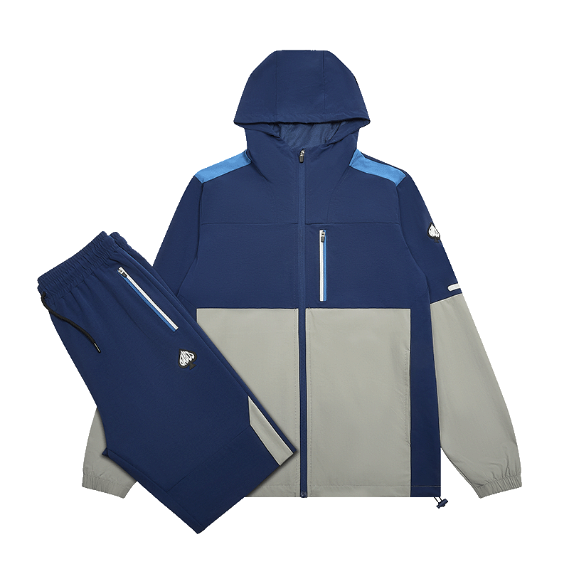 A two-piece athletic tracksuit set consisting of a hooded zip-up jacket and matching pants, shown on a clean white background. The jacket features a color-blocked design with navy blue, light blue, and light gray panels, while the matching pants are solid navy blue.