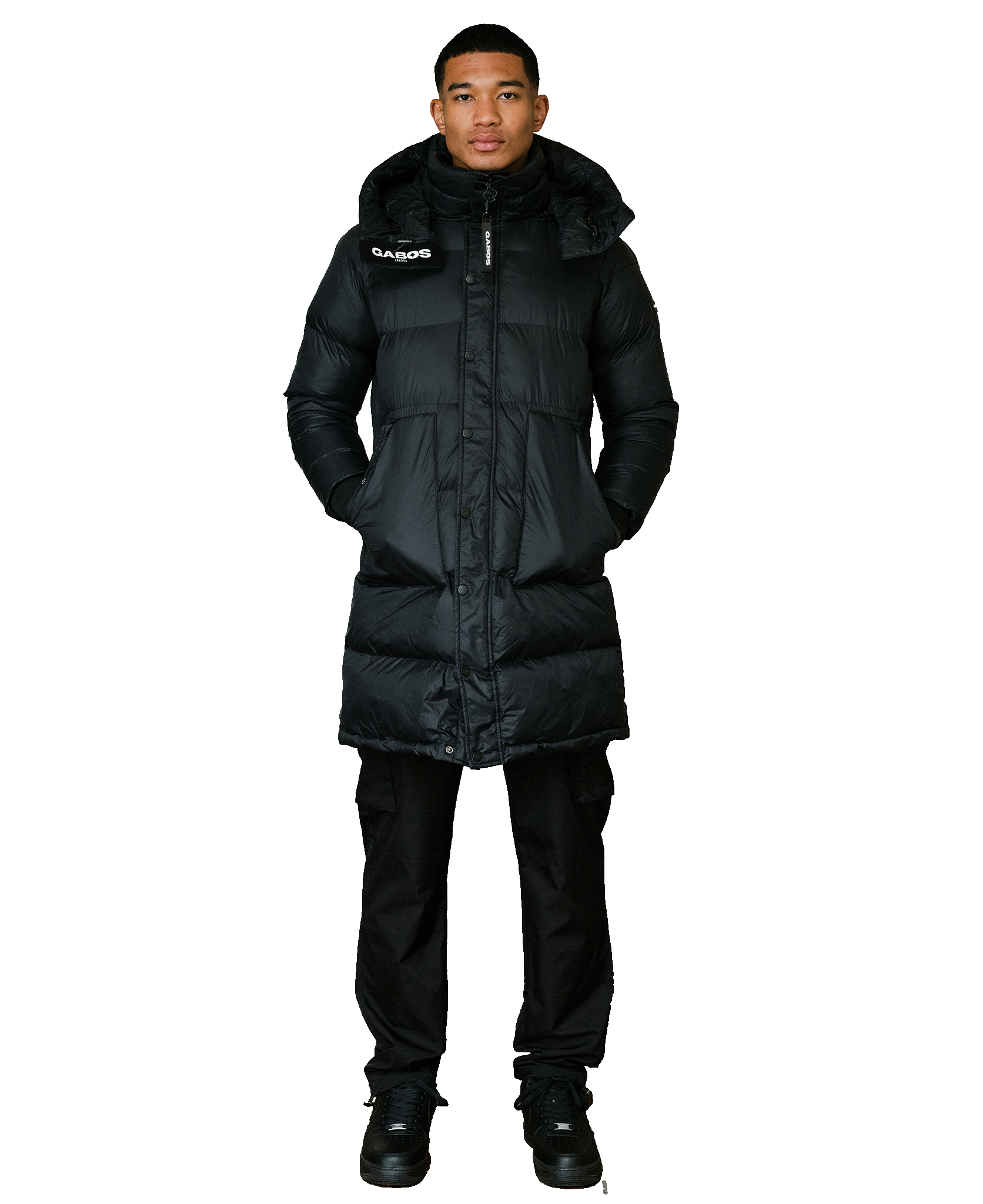 A man modeling a long black puffer coat with a high collar, front zipper, and a visible 'CLIMBER' logo patch on the left chest, paired with black pants and black shoes against a plain white background.