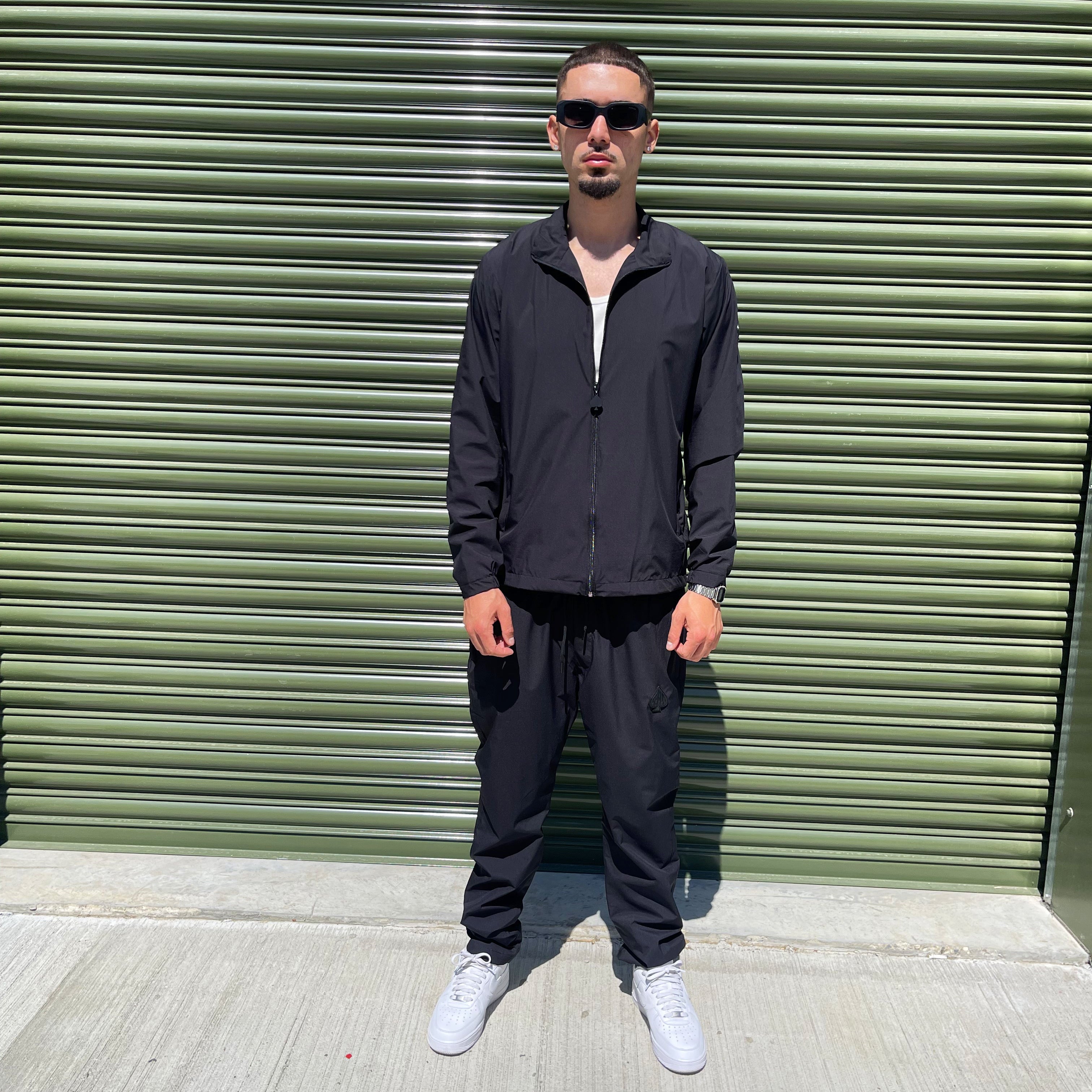 Streetwear model in black Gabos London 3-piece tracksuit set featuring zip-up jacket and matching bottoms, styled windbreaker set